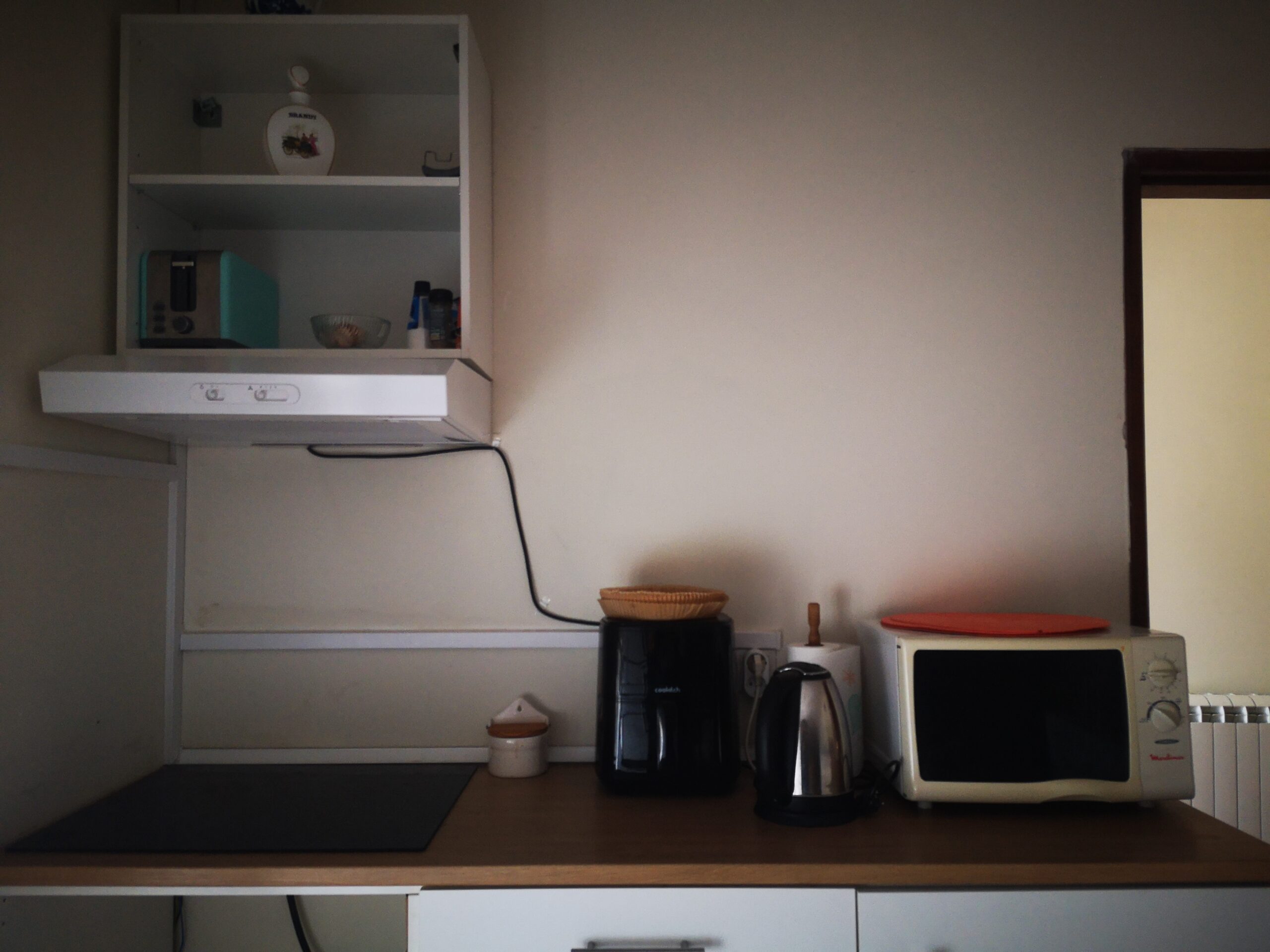 Detalhe da cozinha: balc�o com placa de indu��o moderna com 4 discos, Air-Fryer, forno micro-ondas, exaustor e arm�rio superior de parede