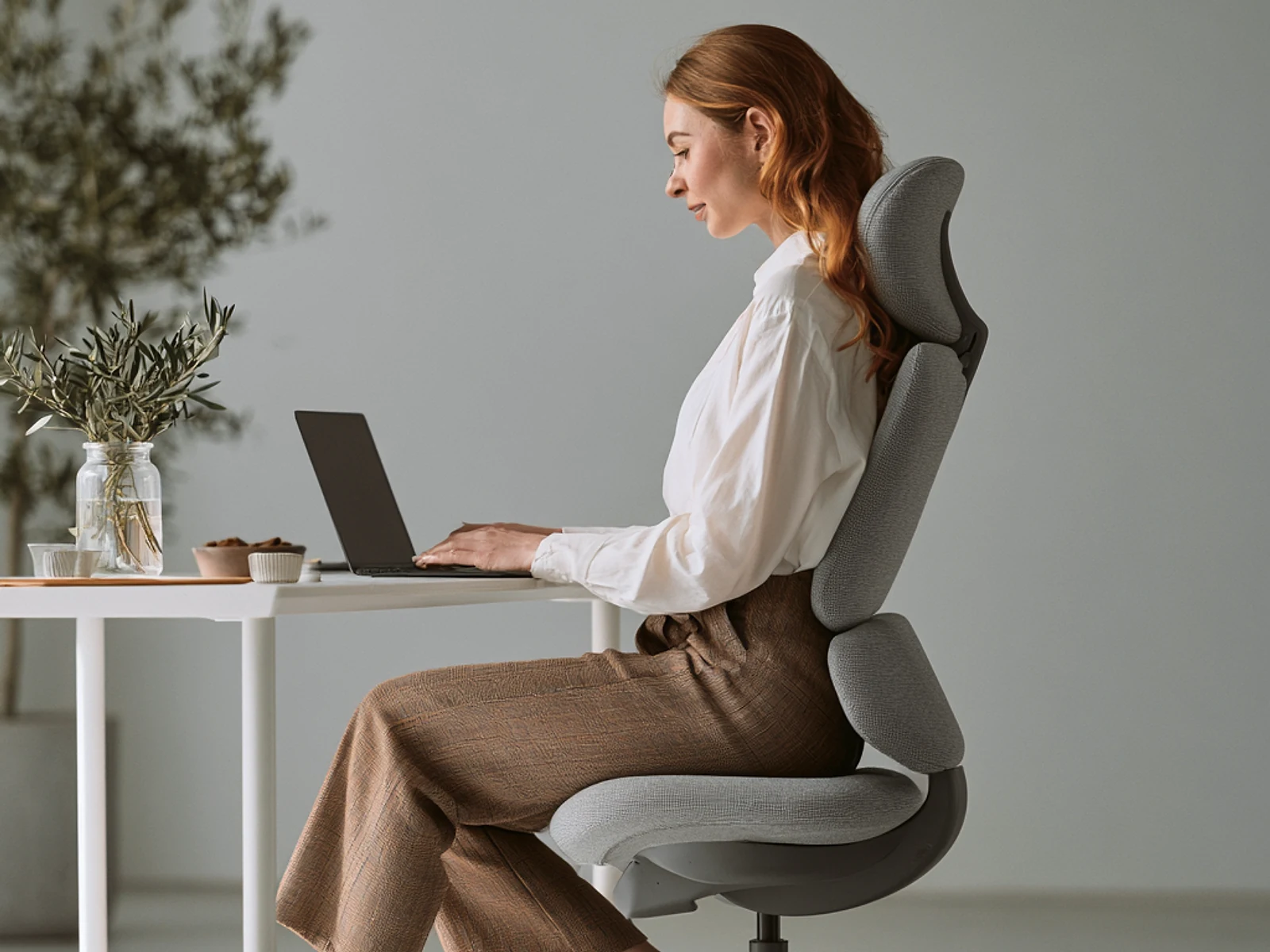 Ilustração: cadeira de escritório ergonómica com apoio lombar regulável, junto a uma secretária de trabalho